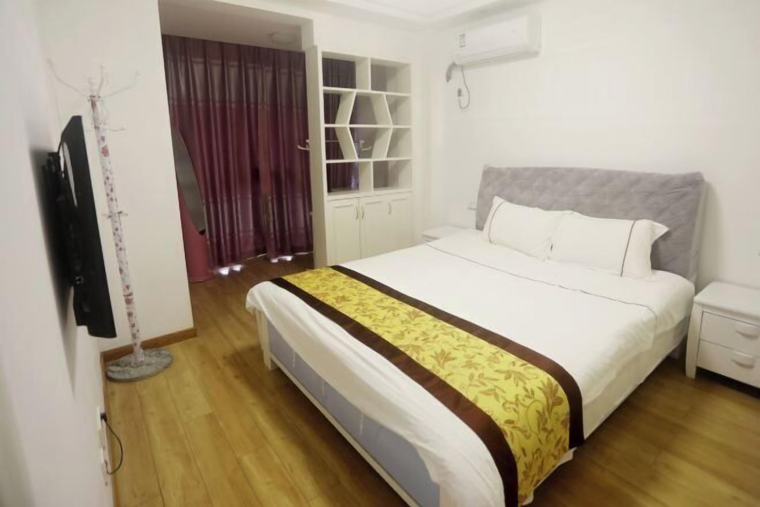 A bedroom with a bed, a wardrobe, a TV, and a curtain.
