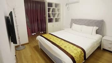 A bedroom with a bed, a wardrobe, a TV, and a curtain.