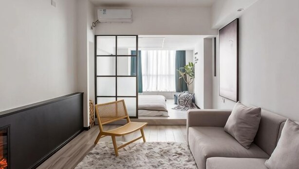 A modern living room with a fireplace, a sofa, a chair, and a view through a sliding door to a balcony. - Huayuan Homestay (Huangshang Scenic Area South Gate) (Huangshan City)