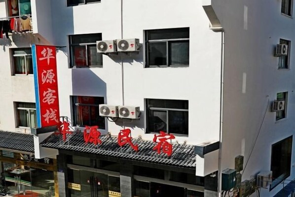 A hotel with a red sign, multiple air conditioning units, and a clear view of the building's facade.