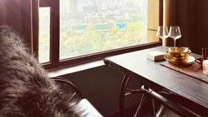 A hotel room with a city view, a dining table with a gold bowl and wine glasses, and a fur throw on the chair. - Huayuan Homestay (Huangshang Scenic Area South Gate) (Huangshan City)