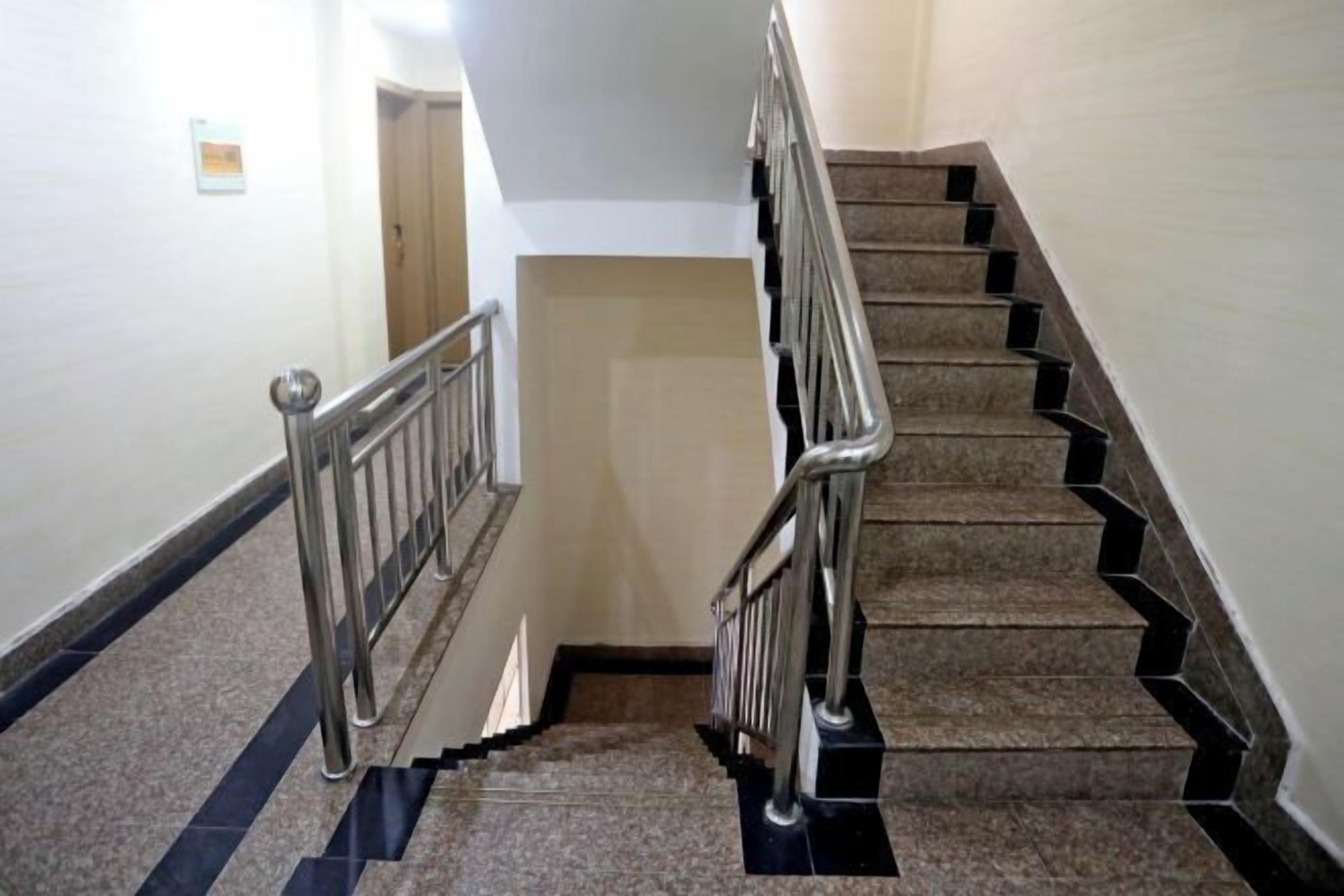 A staircase with metal railings, carpeted steps, and a handrail.