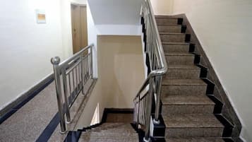 A staircase with metal railings, carpeted steps, and a handrail.