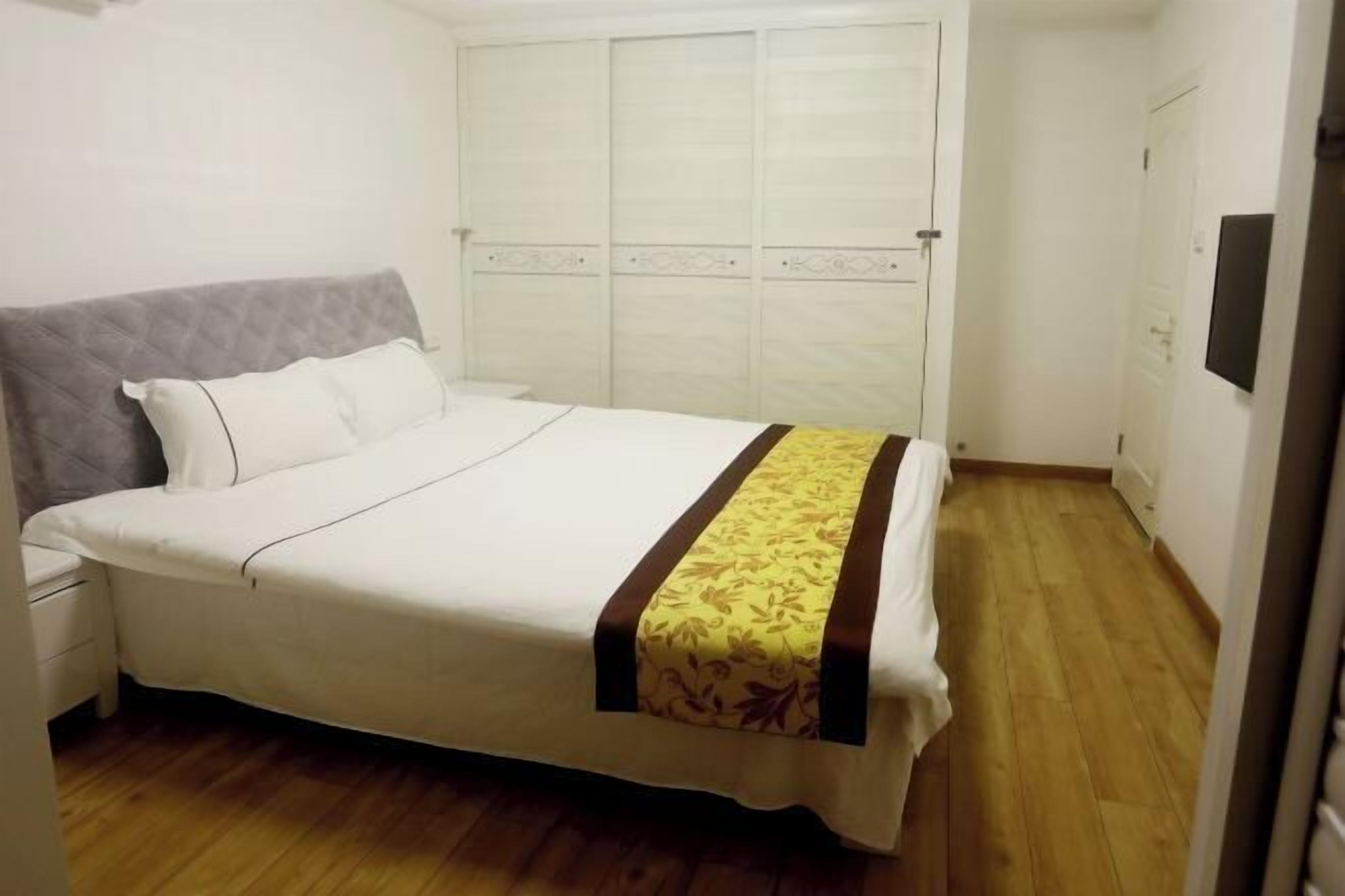 Une chambre à coucher comprenant un lit, une table de chevet, une armoire et un téléviseur.