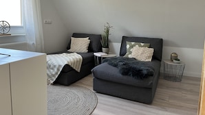 Ein moderner, kompakter Wohnraum mit zwei Sofas, einem kleinen runden Tisch und einem Blumentopf.