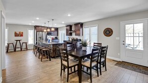 A spacious kitchen with a central island, wooden chairs, and a dining table.