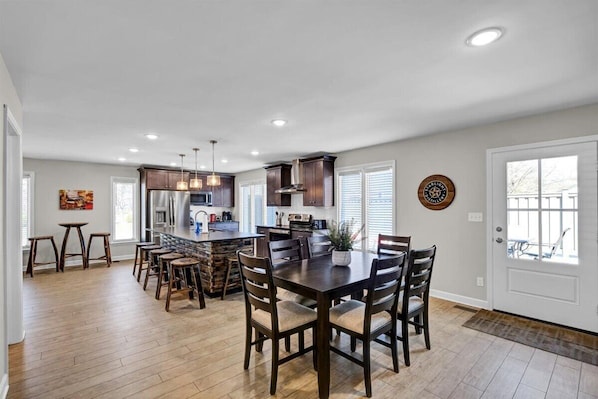 A spacious kitchen with a central island, wooden chairs, and a dining table.