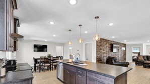 A modern kitchen with dark wood cabinets, a large island, and pendant lighting.