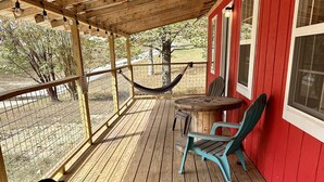 Un’area esterna con veranda in legno, una rete da campeggio, un tavolo e delle sedie.