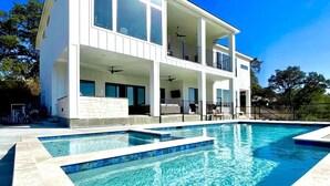 Et moderne hus med to etager og en stor, rektangulær swimmingpool foran.