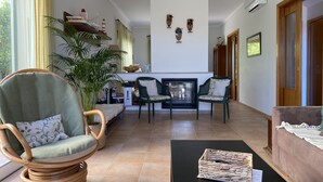 Ein geräumiges Wohnzimmer mit Kamin, bequemen Sitzmöglichkeiten und einer großen Pflanze.