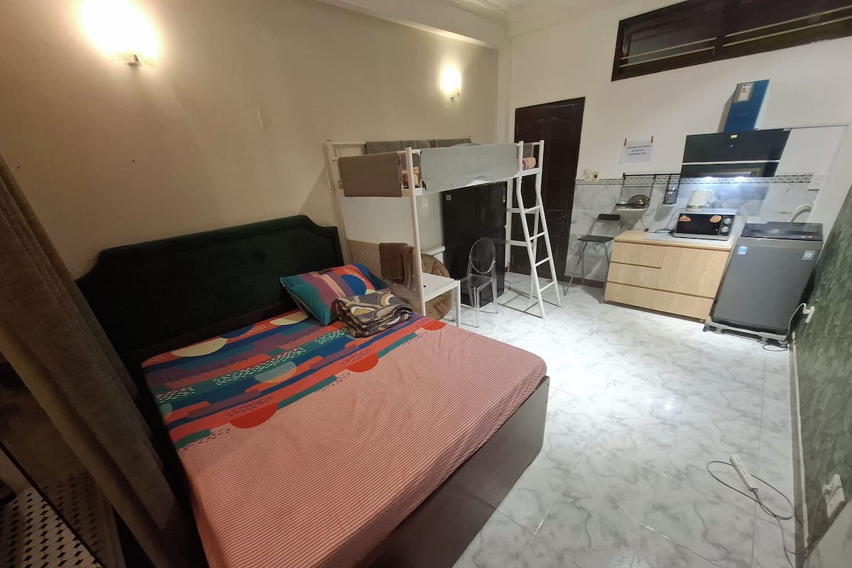 Une petite pièce comprenant un lit, un bureau, une chaise et un coin cuisine.