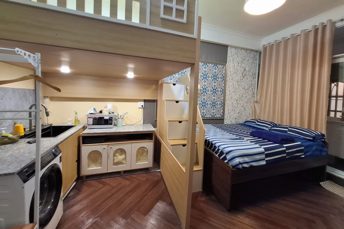 Een compacte kamer met een stapelbed, een kitchenette en een kleine badkamer.