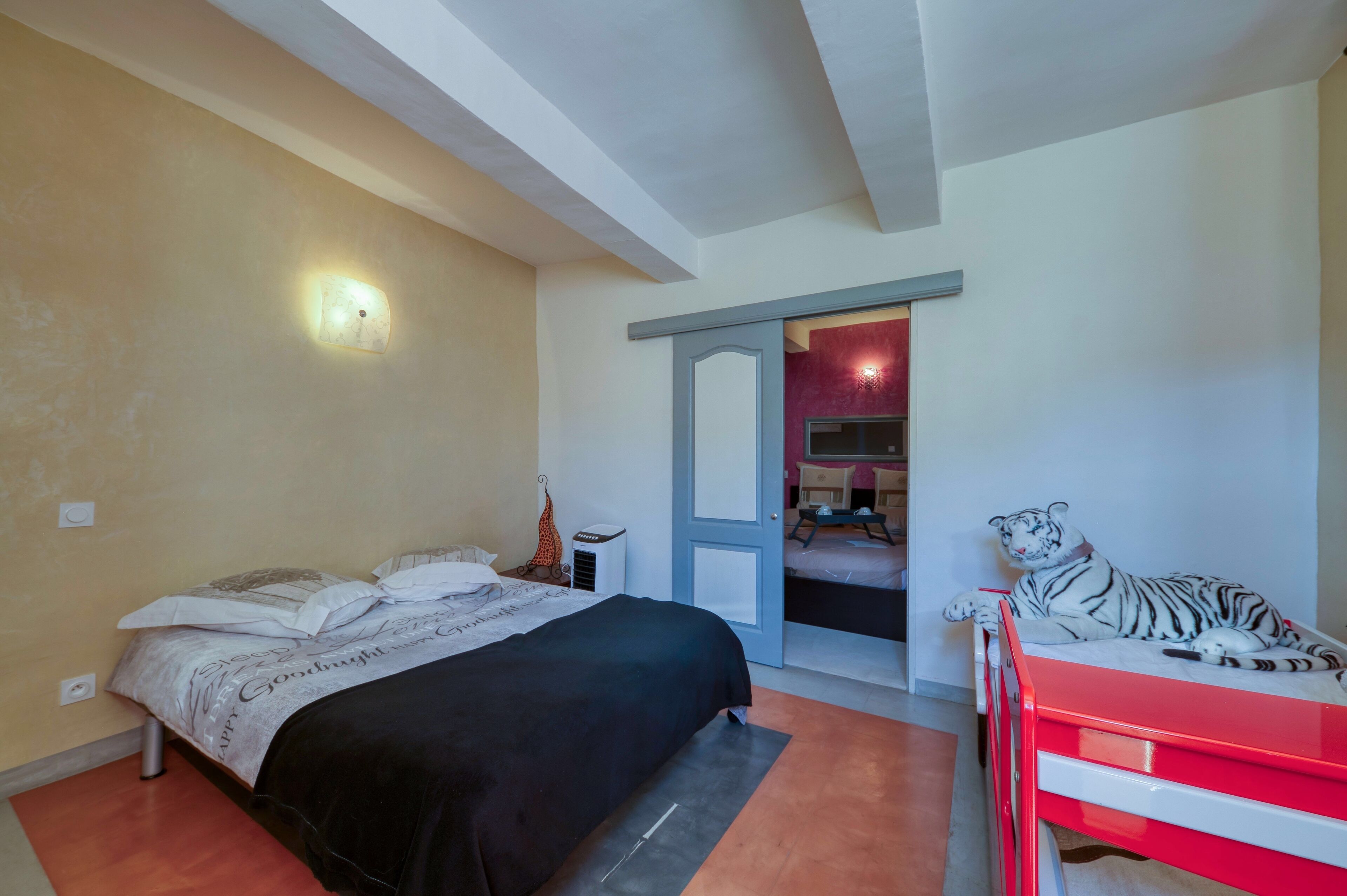 A bedroom with a bed, a red dresser, and a tiger statue.