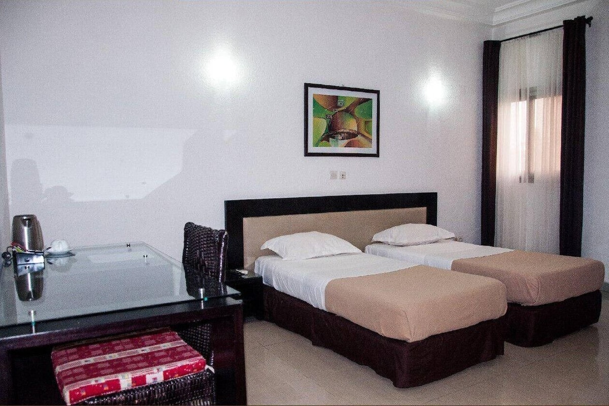 Una habitación de hotel con una cama, un escritorio, una silla y un cuadro en la pared.