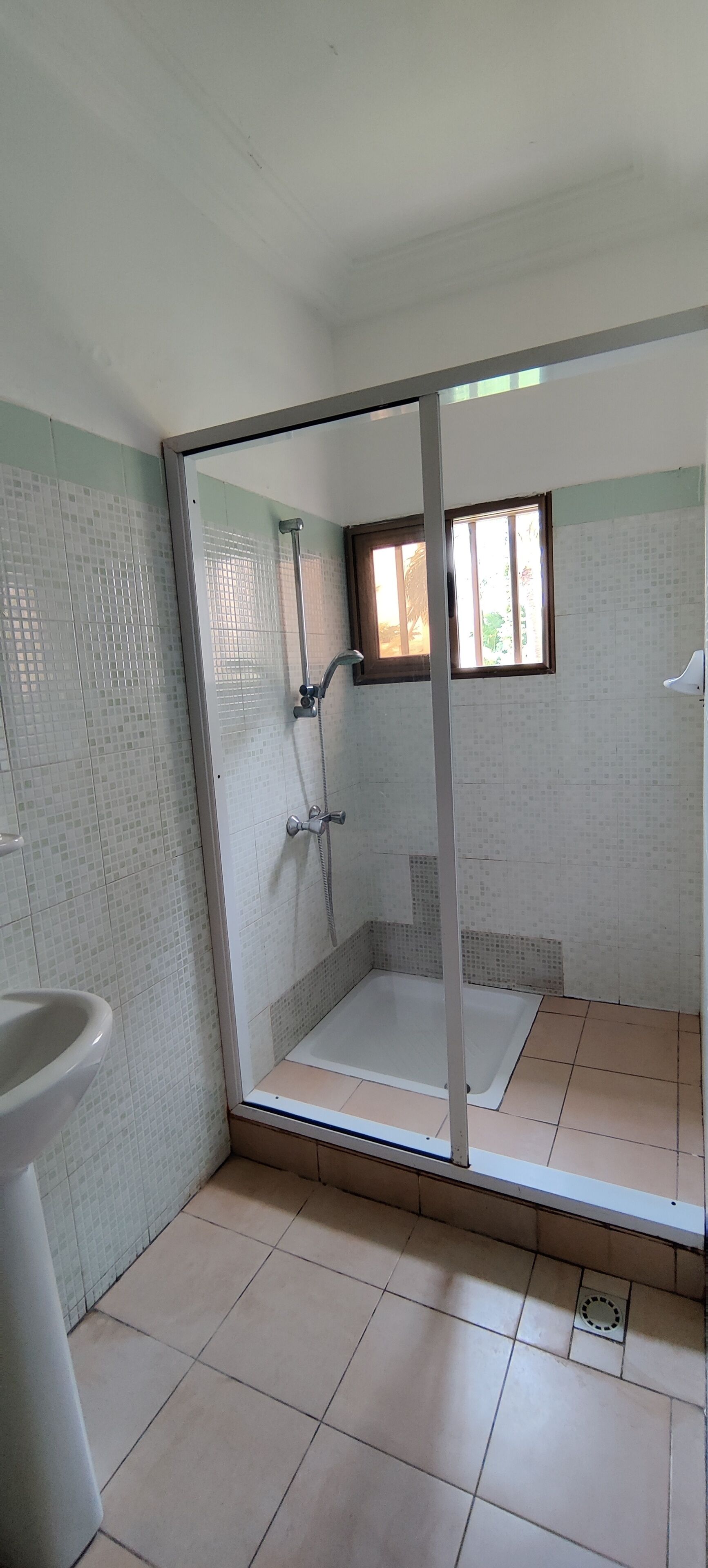 Un baño con cabina de ducha de vidrio, inodoro y paredes de azulejos.