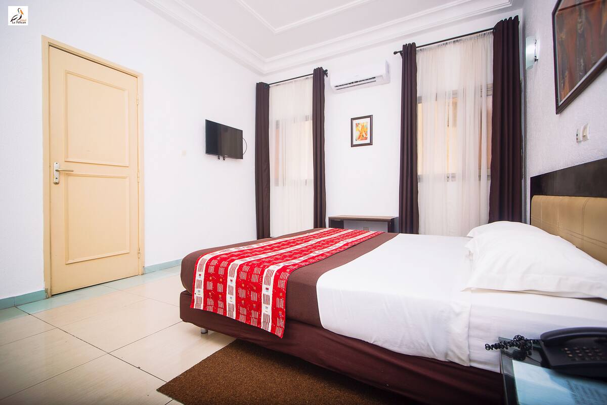 Una habitación de hotel con una cama, un escritorio, una silla, un televisor y una puerta.