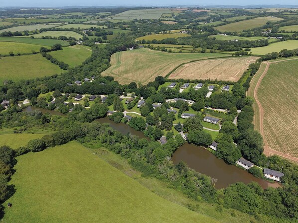 A rural landscape with a cluster of houses surrounded by fields and a river.