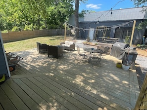 A wooden deck with outdoor furniture, a barbecue grill, and a string of lights.