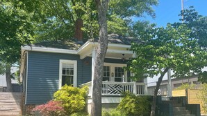 Une maison d’habitation avec un porche à l’avant, une cheminée et un petit jardin.