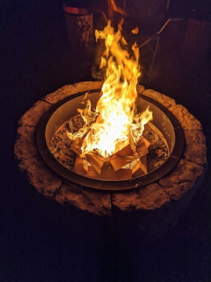 A circular fire pit with logs and flames.