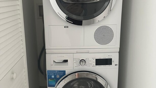 A stacked washer and dryer unit with control panels and a Wi-Fi symbol. - Smart Brickell Hotel (Miami)