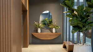 A modern interior with a wooden shelf holding decorative plants, a large mirror, and a seating area. - Smart Brickell Hotel (Miami)