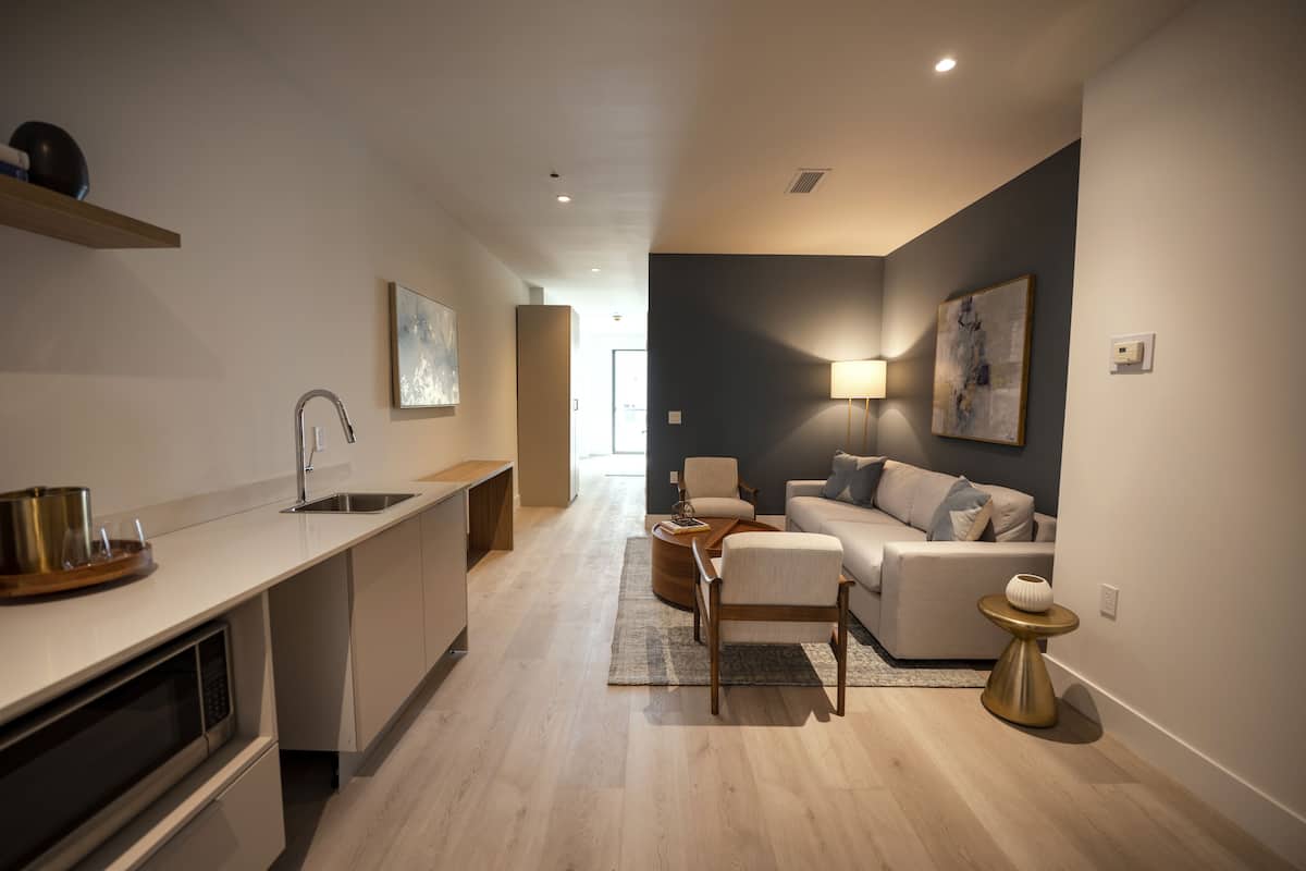 A modern kitchen with a built-in dishwasher and a dining area with a round table and chairs.