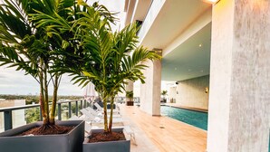 A rooftop pool area with two large planters containing palm trees, lounge chairs, and a view of the cityscape. - Smart Brickell Hotel (Miami)