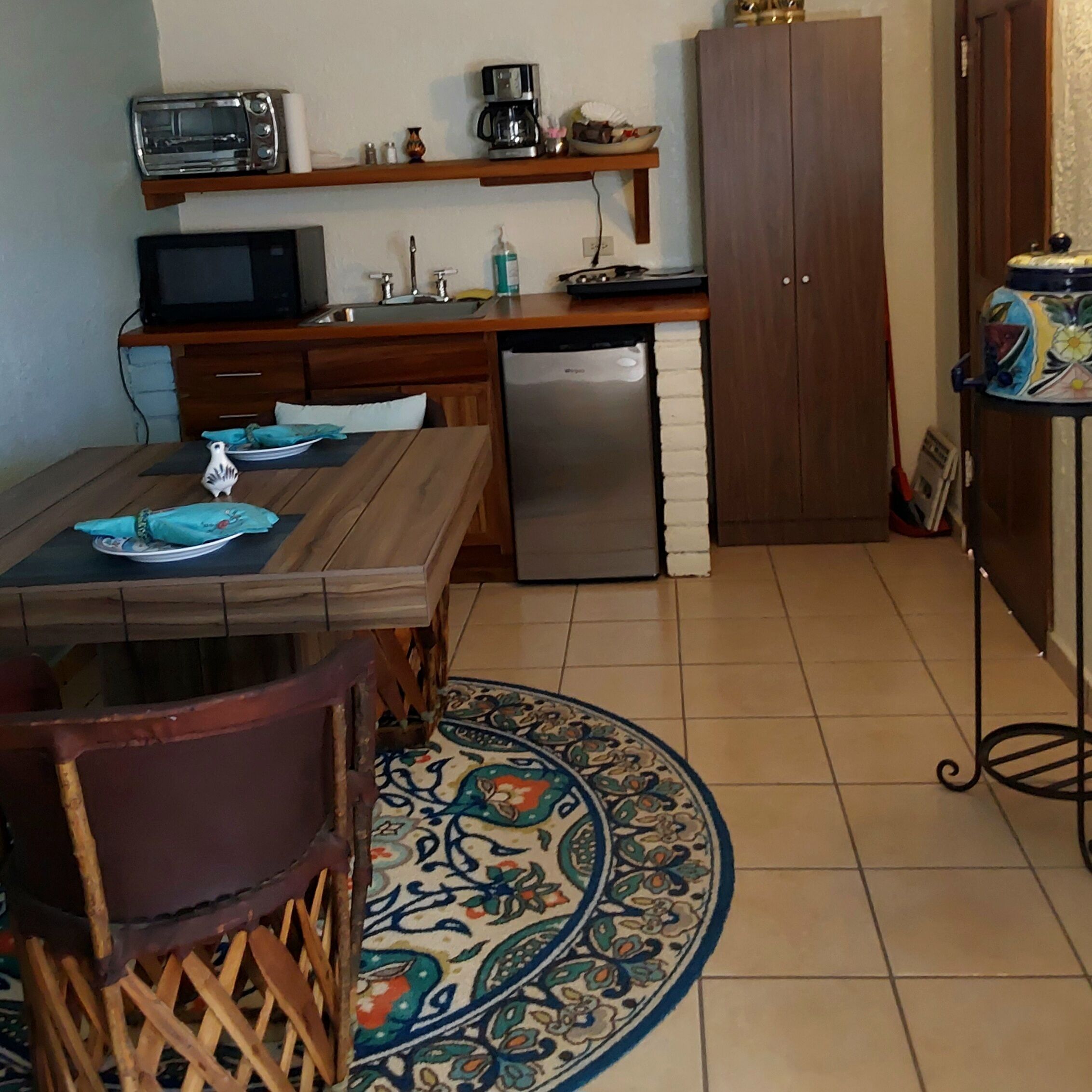 A compact kitchen with a dining table, a microwave, a coffee maker, and a refrigerator.