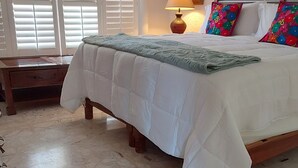 A bedroom with a bed, a nightstand, a lamp, and a painting on the wall. - Romantic Villa Beach House (San Carlos)