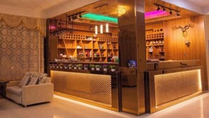 Een bar met houten planken en een decoratie van een hertenkop, een zachte zithoek en een patroonbehang.