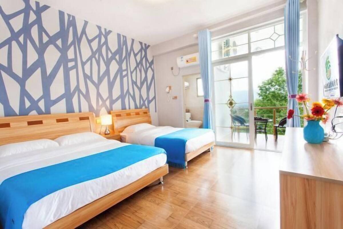 Une chambre d’hôtel avec deux lits, une grande fenêtre et un balcon offrant une vue.