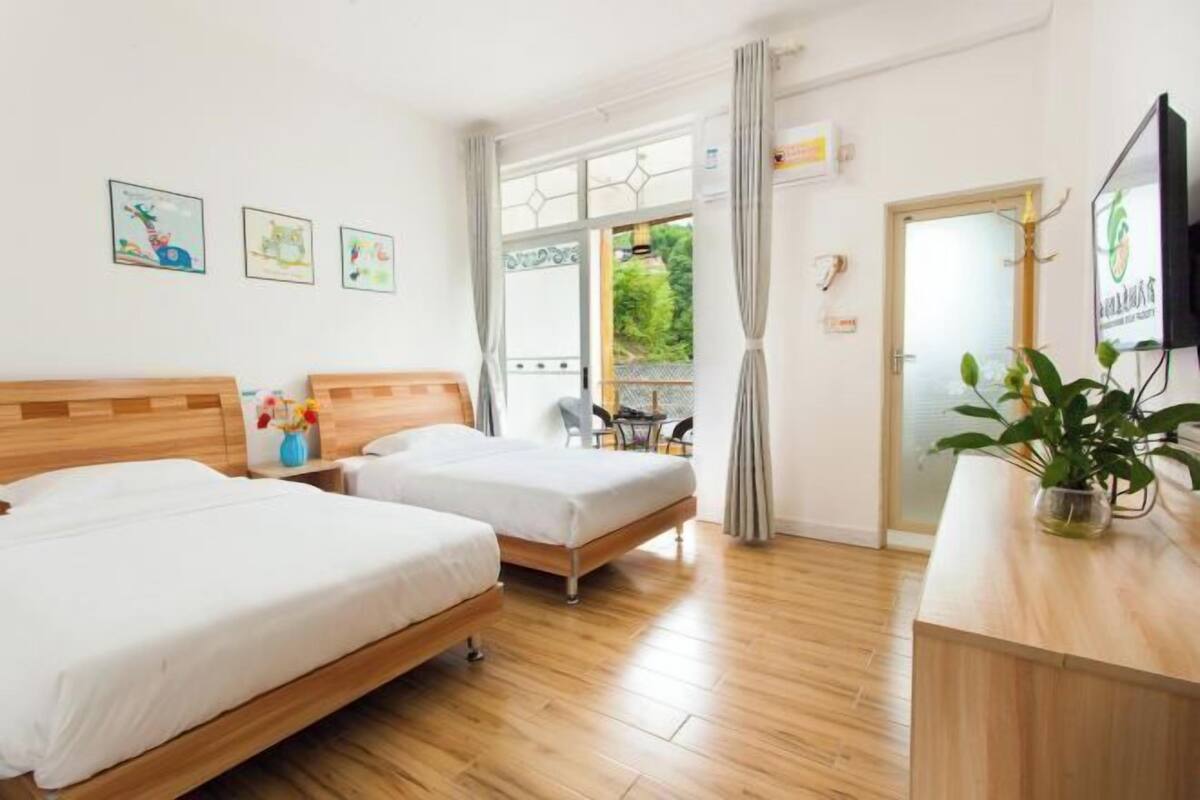 Une chambre d’hôtel avec deux lits, un bureau en bois, une télévision et une fenêtre avec des rideaux.