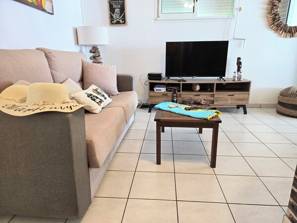 Un salon comprenant un canapé, une table basse, un téléviseur et une lampe décorative.