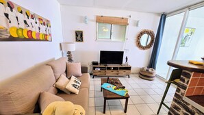 Un salon comprenant un canapé, une table basse, un téléviseur et un coin repas avec une table et des chaises.