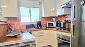 Une cuisine compacte dotée d’un îlot central intégré, d’un four à micro-ondes, d’une machine à café et d’un réfrigérateur.