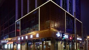 Un hotel amb una façana moderna, grans finestres i senyalització il·luminada.