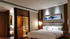 Habitació d'hotel moderna amb un llit, un quadre a la paret i una porta corredissa que dona a un bany.