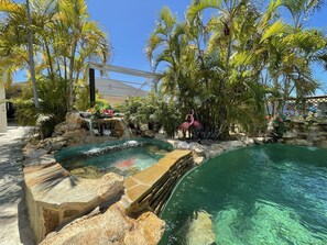 A pool area with a waterfall, palm trees, and a pink flamingo statue. - BEST House in Marathon With Ocean View! (Marathon)