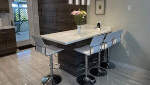 A modern kitchen with a large island, bar stools, pendant lighting, and a welcome sign. - BEST House in Marathon With Ocean View! (Marathon)