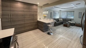 A modern kitchen with dark wood cabinets, a central island, and a dining area with a grey sofa and coffee table. - BEST House in Marathon With Ocean View! (Marathon)