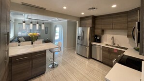 A modern kitchen with dark wood cabinets, stainless steel appliances, and a central island with bar stools. - BEST House in Marathon With Ocean View! (Marathon)