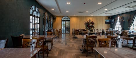 Un restaurant spacieux avec de hauts plafonds, de grandes fenêtres et un arrangement floral central.