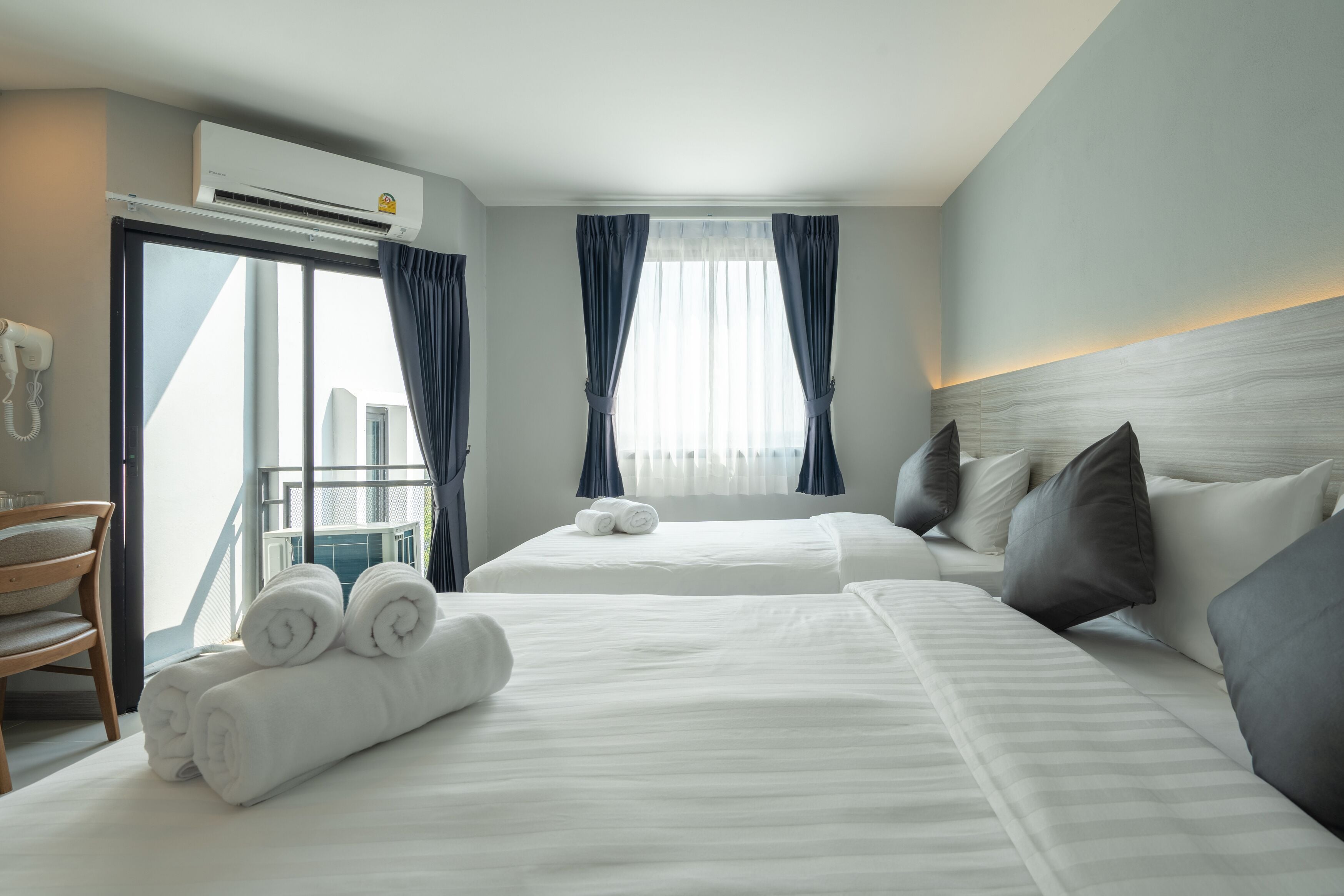 Ein Hotelzimmer mit zwei Betten, einem Balkon und einer Klimaanlage.