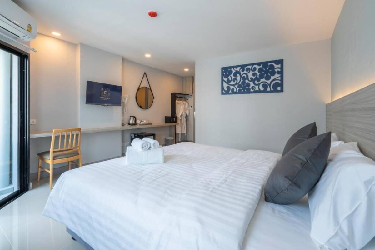 Ein Hotelzimmer mit Bett, Schreibtisch, Stuhl, Fernseher und einem Badezimmer mit Handtuchhalter.