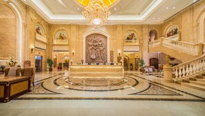 A grand lobby with a central reception desk, a chandelier, a marble floor, and a staircase. - Vienna International Hotel (Shanghai)