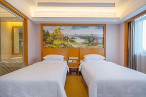 A hotel room with two beds, a painting of a landscape on the wall, and a window with curtains.