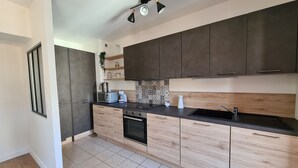 Una cocina moderna con armarios oscuros, encimera negra y salpicadero de azulejos.
