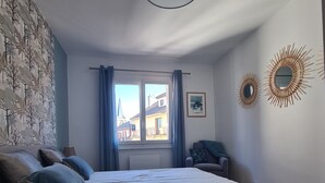 Un dormitorio con una cama grande, vistas a través de una ventana y espejos decorativos en la pared.